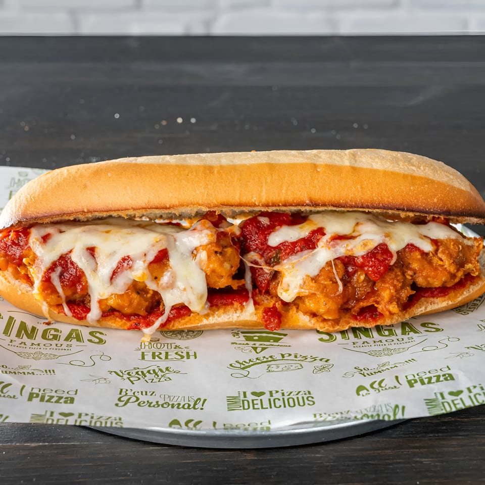 A chicken parmesan sub sandwich with melted mozzarella cheese and red sauce on branded paper.
