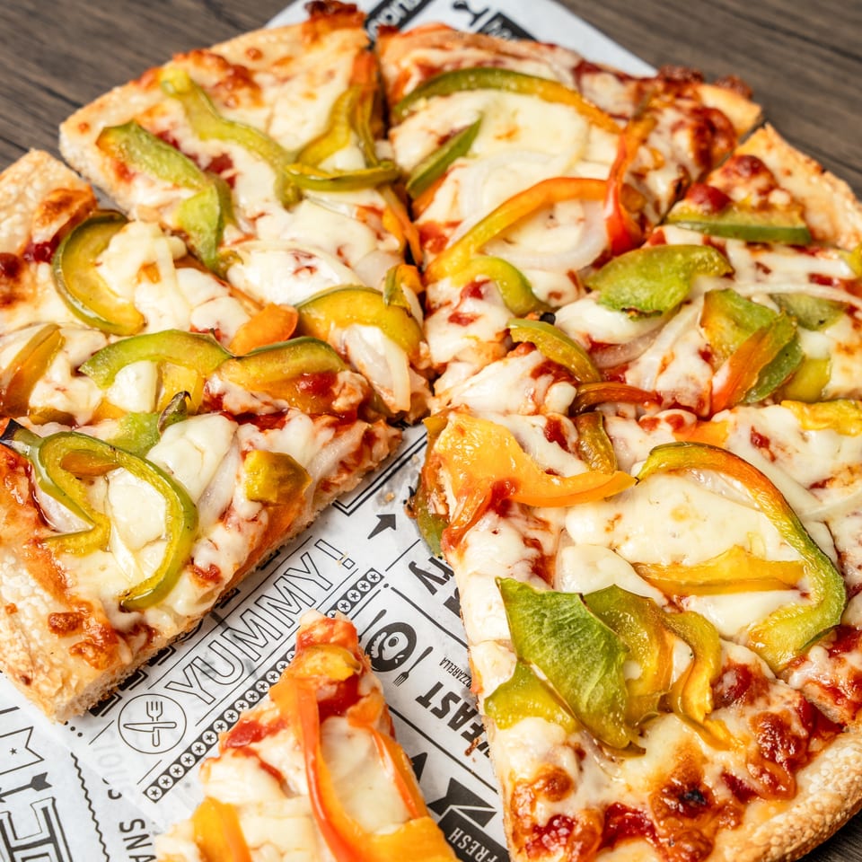 Singas Famous Pizza's sliced vegetable pizza with melted cheese, green and yellow bell peppers, and onions.