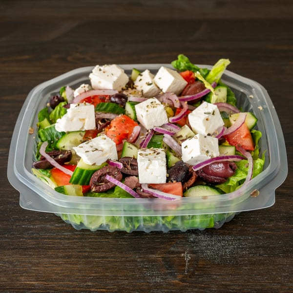 Greek salad with lettuce, cucumbers, tomatoes, red onions, black olives, and feta cheese.