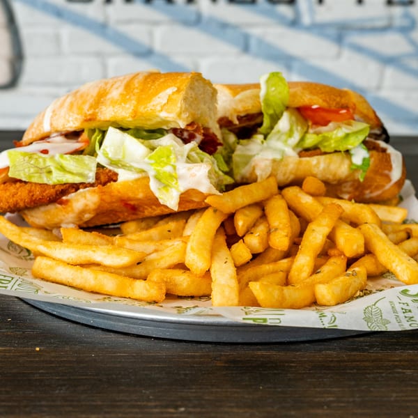 A crispy chicken sandwich with lettuce, tomato, and sauce, served with golden french fries.